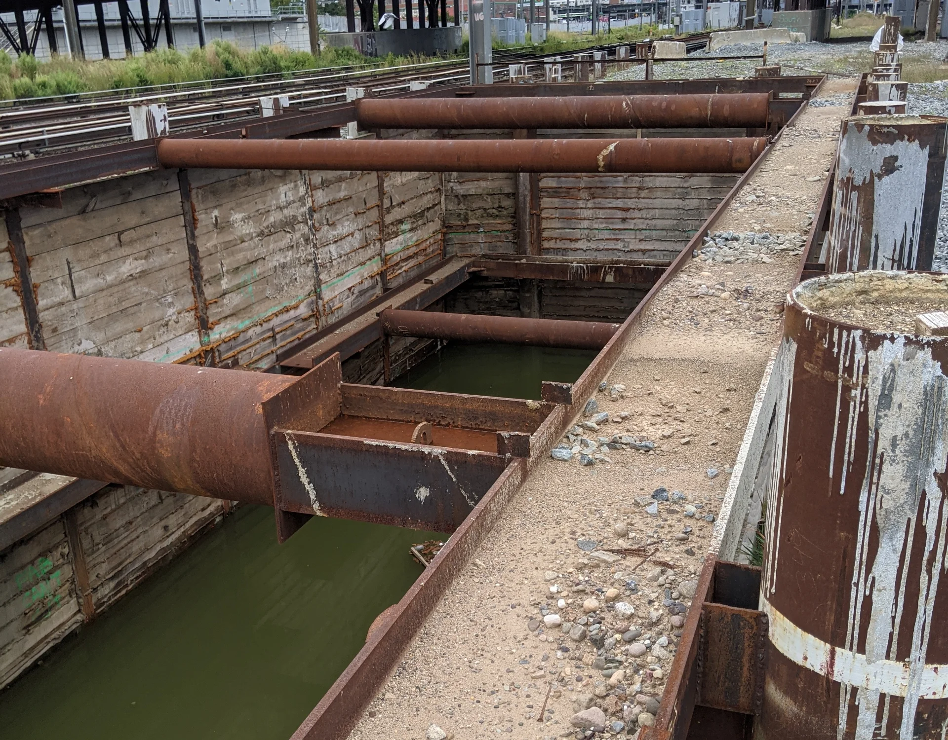 project site before with rusty pipes and water inside of tunnel