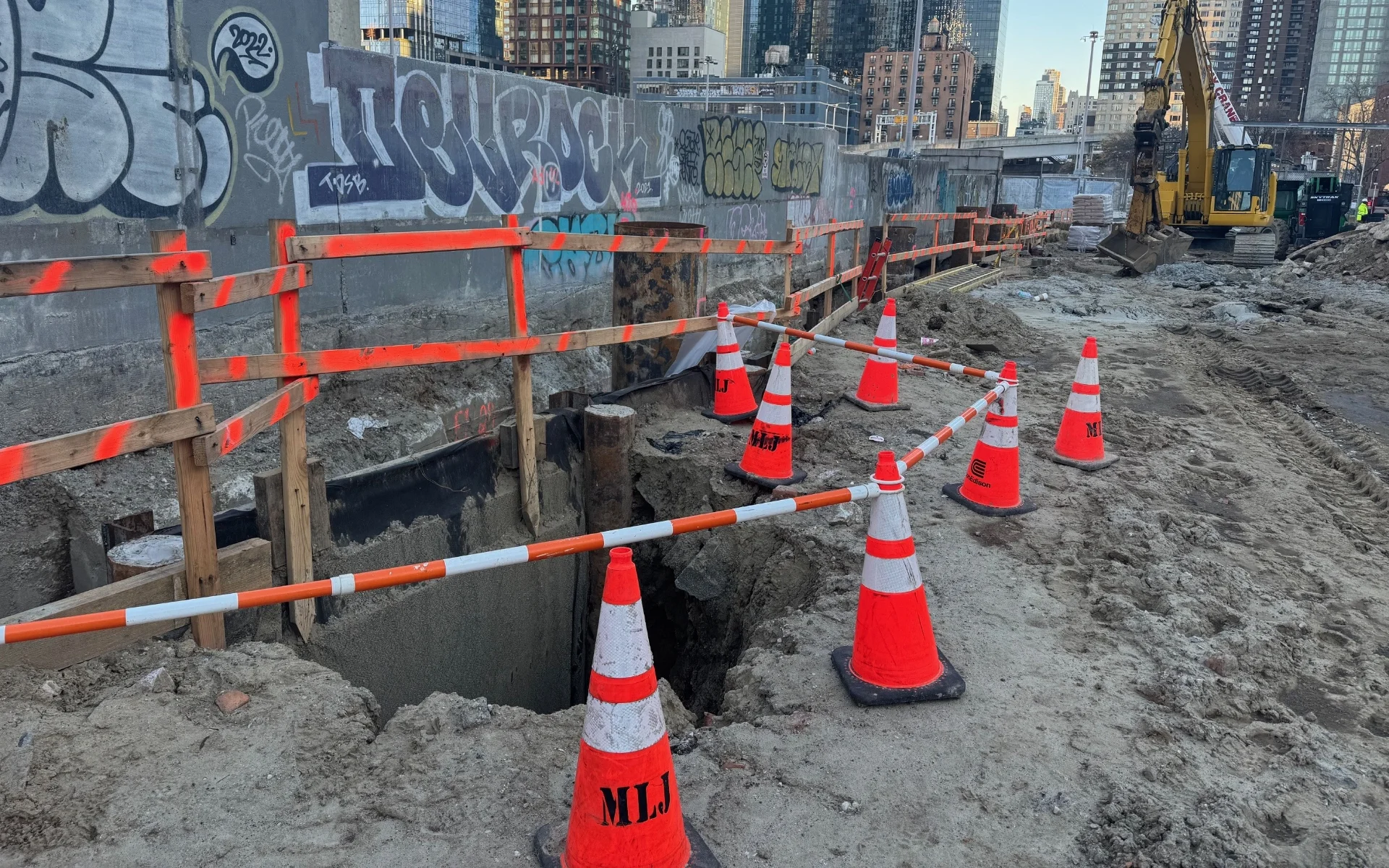large hole at construction site with safety cones